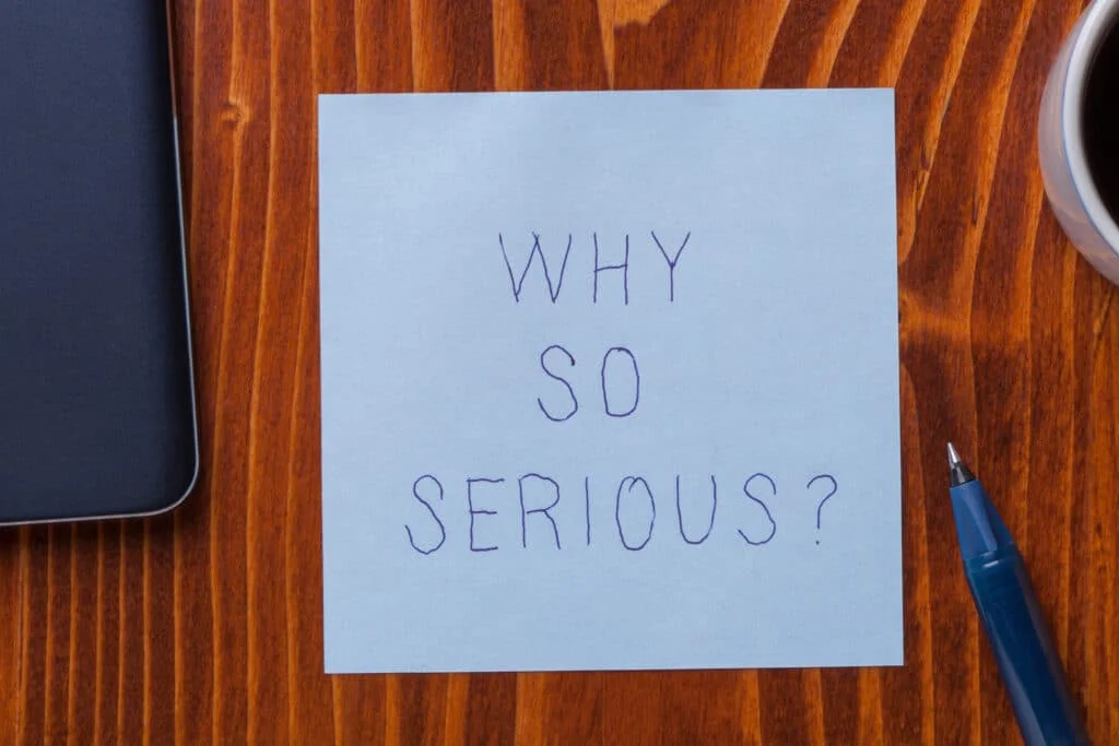 A note on a desk with the words "why so serious?" written on it